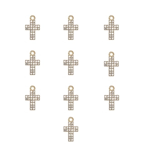 Macro view of 10 golden alloy cross charms with sparkling crystals for jewelry making