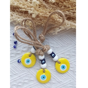 Detailed view of three yellow evil eye charms with blue beads and rustic hemp rope texture