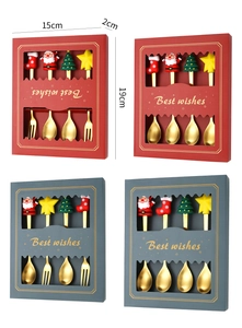 Close-up of golden Christmas spoons and forks set with festive dolls in gift packaging