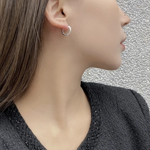 Close-up of minimalist silver hoop earrings on a model's ear showing polished metal finish