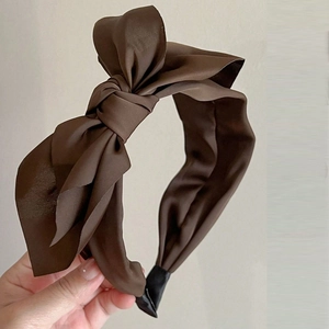 Detail of a brown satin wide headband with a large double-layered bow for women