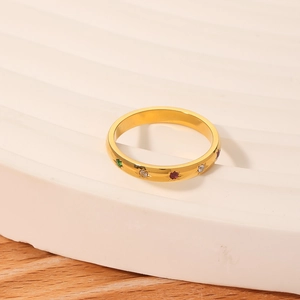 Golden stainless steel star ring with colorful zirconia stones on a white wavy pedestal