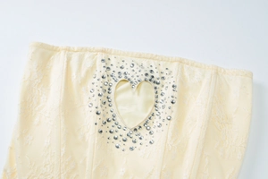 Dettaglio in pizzo giallo chiaro con intaglio a cuore di strass su un abito aderente