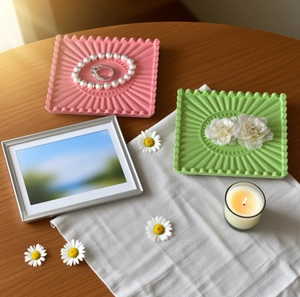 Vue détaillée des motifs tournesol sur les plateaux à bijoux en résine rose et vert