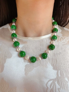 Detail of vintage necklace with green textured glass beads and white pearls on neck