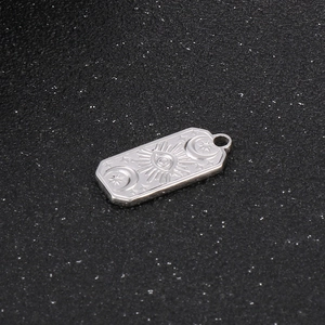 Detailed view of stainless steel rectangular pendant with celestial sun and moon motifs