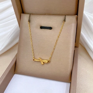Minimalist gold bow necklace crafted from titanium steel displayed in a premium jewelry box