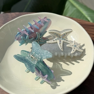 Detail of starfish hair claw clips with glitter finish and rhinestones in ceramic tray