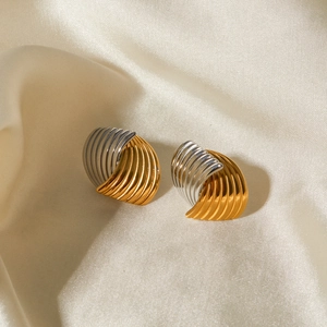 Macro shot of gold and silver textured earrings on champagne silk background