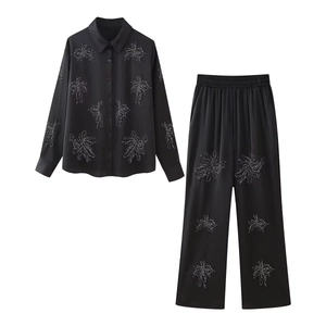Women's black satin set with abstract floral print featuring long sleeve shirt and wide pants