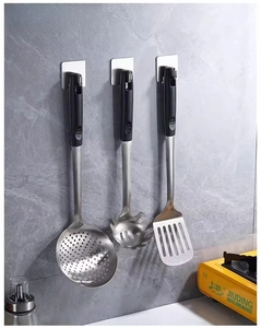 Wall-mounted stainless steel utensil set hanging on a metallic adhesive hook
