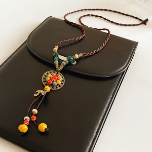 Detailed macro of ceramic leaf pendant and bronze hardware on ethnic braided necklace