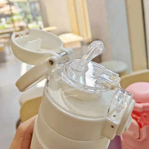 Detail view of the white sports bottle with flip lid, carrying handle, and silicone straw