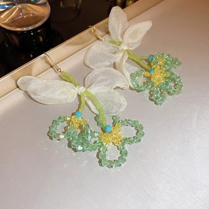 Detail of beaded floral earrings with light green crystals and a delicate organza bow