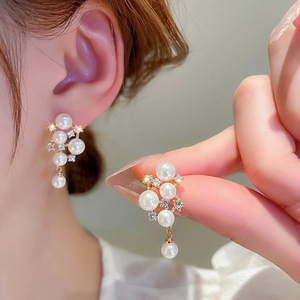 Detail of elegant gold plated pearl earrings with sparkling zircon crystals for women
