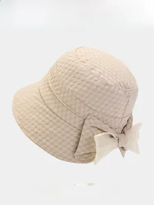 Detailed macro view of beige bucket hat featuring textured relief and large mesh bow decoration