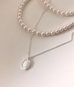 Close-up of layered 925 silver necklace with pink pearls and oval opal pendant