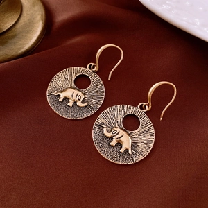 Macro de boucles d'oreilles relief éléphant vintage sur fond de satin rouge foncé