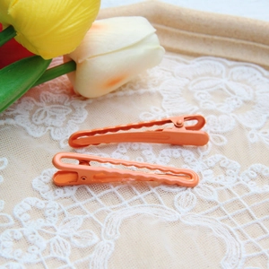 Close-up of orange gradient metal hair clips on a lace background with wooden tray