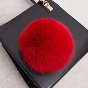 Gros plan d'un grand pompon en fourrure de renard rouge sur un sac à main noir
