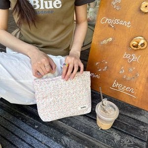 Close-up of floral print cotton pouch with Sozakka label and zipper detail outdoors