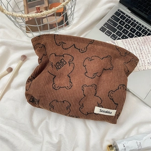 Detailed texture of brown corduroy makeup bag with cute printed bears on a soft white surface