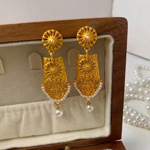 Vintage hollow gold earrings with pearls displayed on a premium jewelry box