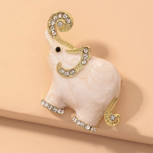 Macro shot of gold elephant brooch with white enamel body and sparkling crystal accents