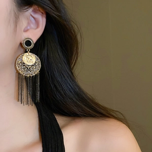 Détail de boucles d'oreilles vintage dorées avec pièce ronde et pompons métalliques