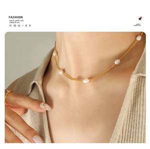 Detail of model wearing a gold flat chain necklace with natural freshwater pearls