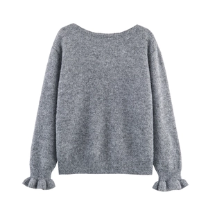 Détail d'un pull en maille grise montrant la texture douce et les poignets à volants