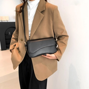 Minimalist black leather crossbody bag with asymmetric wave flap and gold hardware