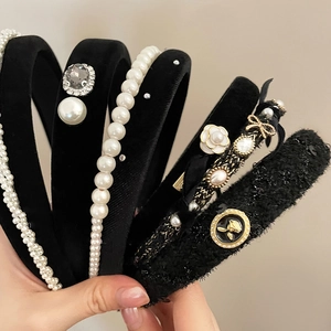 Detail of assorted black velvet headbands featuring pearls, rhinestones and camellia flowers