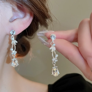Macro shot of silver drop earrings featuring sparkling leaf motifs and pear-cut crystal charms