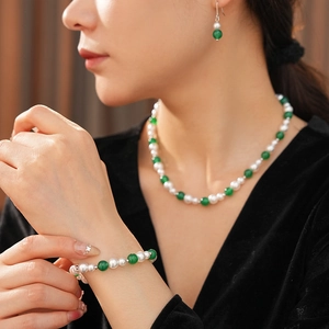 Dettaglio di un set di gioielli vintage con perle e agata verde su una modella elegante