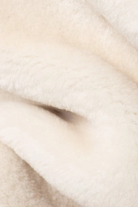 Close-up of soft cream faux fur fabric texture on a warm winter jacket garment