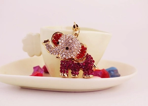 Detail of cute elephant pendant with red and white rhinestones on a heart coffee cup