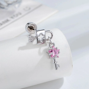 Silver heart lock and key stud earrings with a pink star gemstone on white pedestal