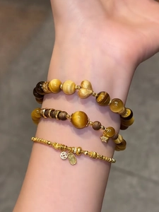 Nahaufnahme mehrlagiger Tigerauge-Armbänder mit goldenen Herz- und Sternanhängern