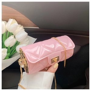 Pink quilted cylinder bag with gold chain strap and pearl detail in a luxury car interior