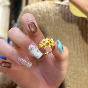 Elegant gold plated matte flower cluster open ring on hand with brown sweater background
