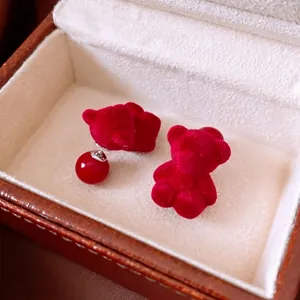 Red flocked teddy bear stud earrings with silver pins displayed in a premium jewelry box