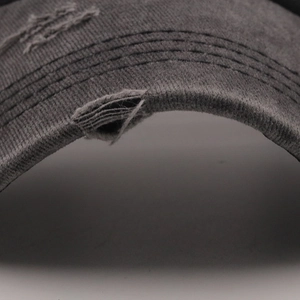 Detail of distressed brim on charcoal washed cotton baseball cap with vintage worn effect