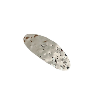 Silver oval geometric metal hair clip with irregular hammered texture on white background