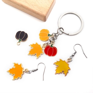 Flat lay of enamel pumpkin and maple leaf pendants for autumn DIY jewelry making