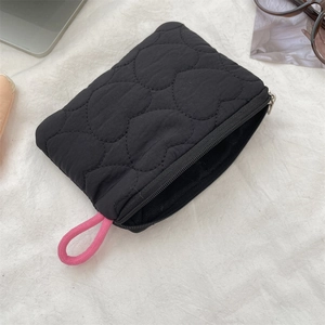 Detail of black heart-quilted mini pouch with pink rope handle and silver zipper closure