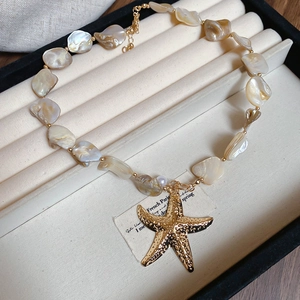Close-up of shell bead necklace with a large gold starfish pendant in a jewelry box