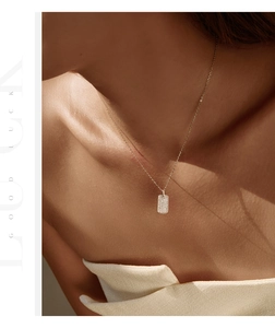 Detailed view of a gold-plated silver necklace with a rectangular moissanite pendant on a model