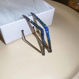 Detail view of geometric silver earrings with dark metal and blue-green gradient rhinestones