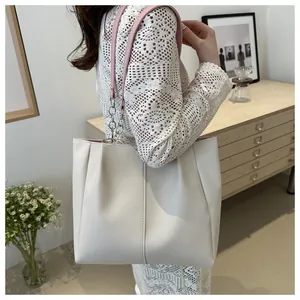 Dettaglio borsa tote bianca minimalista con manici in pelle rosa e catena argentata